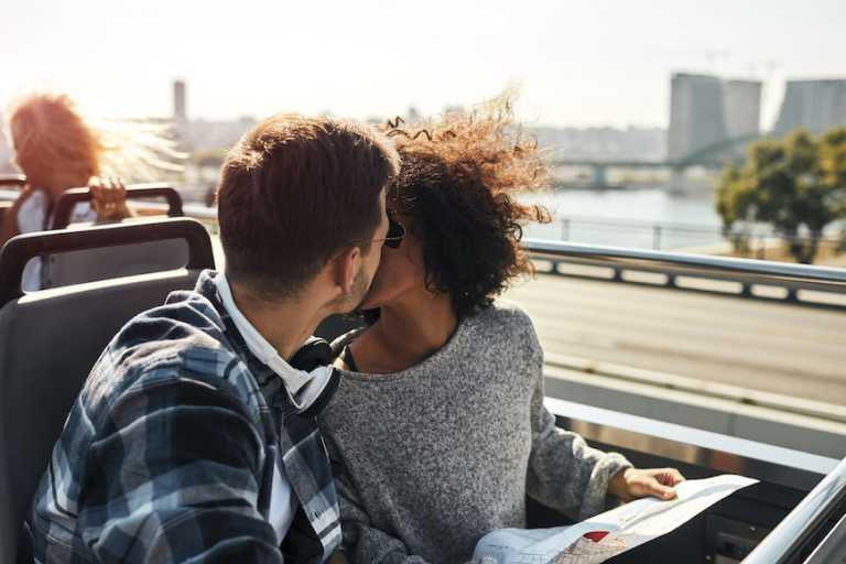 2 people kissing on top of a bus