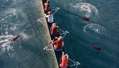 Female crew team rowing on the water.