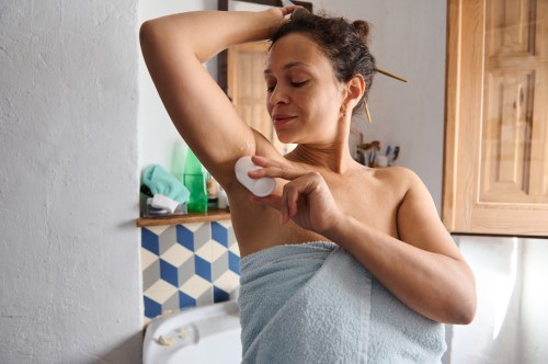 close up of person wrapping in a blue towel with their hair pinned up applied the best natural deodorant to their armpit to stay fresh all day long