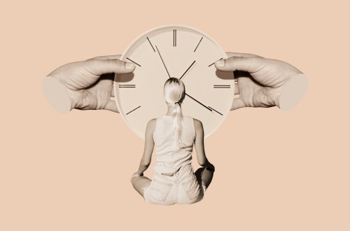 A woman is seen sitting and looking at an oversized clock.