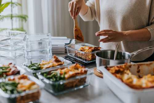 A woman meal prepping in containers in her kitchen