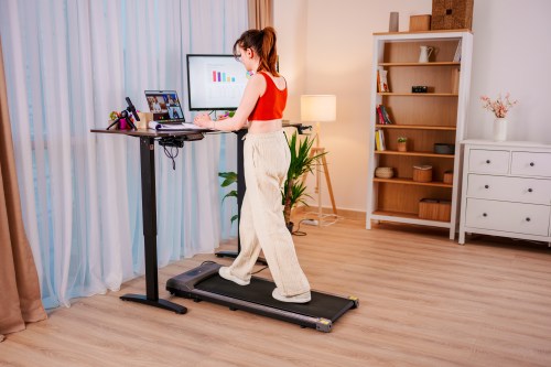 Young Business Woman working at an Ergonomic standing desk while walking on a walking pad, online meeting while checking Bitcoin or stock market price chart on a digital exchange, cryptocurrency future price action prediction