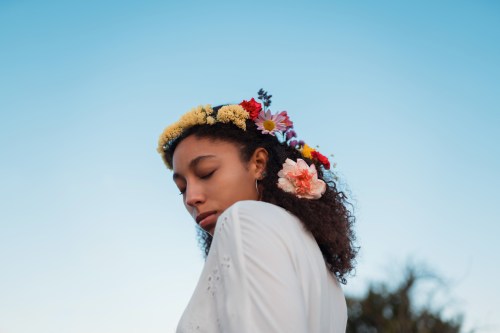 A young woman wears a flower crown outside.