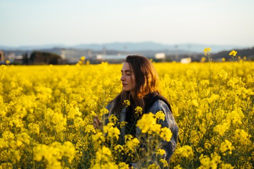 A young woman poses in in a field of flowers during sunset.