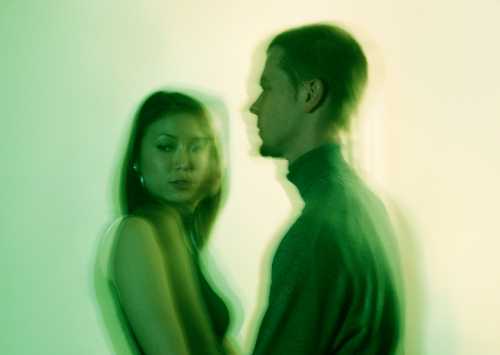 blurred image of a couple looking away from each other to represent signs your body is rejecting someone in a relationship against a green background