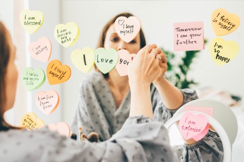 Woman placing stickers with positive affirmations on the mirror.