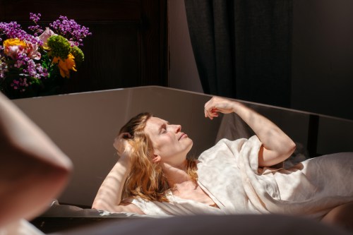 A woman is seen relaxing on a couch at home, enjoying the sunlight