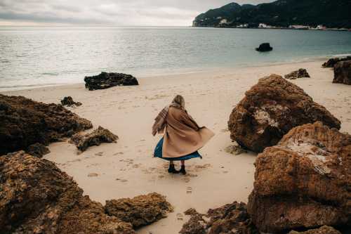 Woman in a beige coat on a beach in winter.