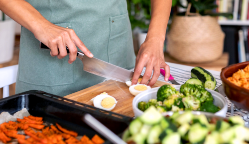 Detail of cropped woman with apron cooking healthy meals cutting boiled eggs at table with a knife from a knife set sale