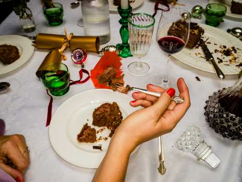 Close Up Over The Shoulder View Hands Of Woman Eating Chocolate Dessert At Dining Table