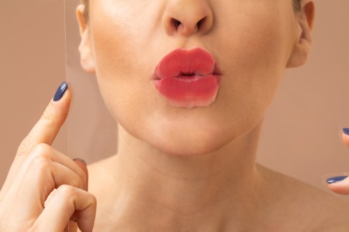 Unrecognisable Caucasian woman model posing and leaving lipstick mark from Monika Blunder lippies on a glass.