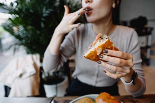 close up of person eating a sandwich while at the kitchen in their house to show food poisoning and lactose intolerance