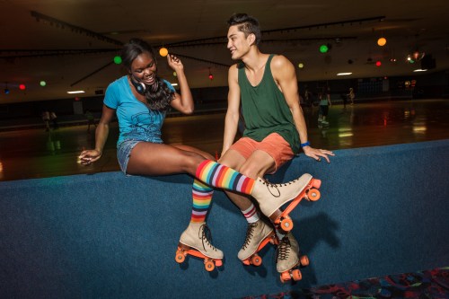 Two young friends sitting in a roller rink where skates