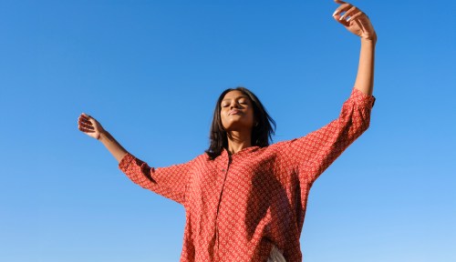 A woman in a colorful shirt looks towards the sky, as a visual for your March 23, 2025 weekly horoscope.