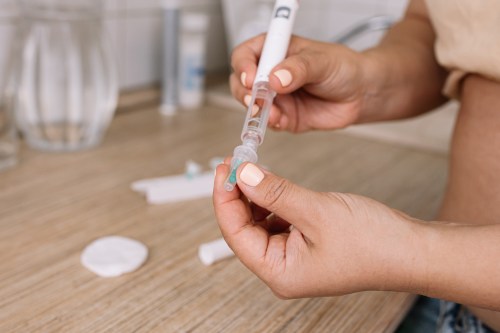 Person holding an Ozempic injection pen on top of a wooden table