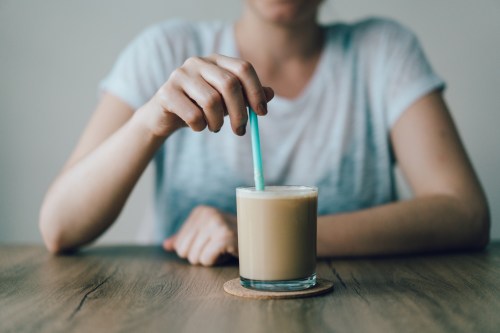 Young woman mixing ice coffee