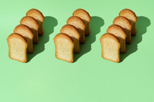 Three rows of four slices of toasted bread on a green background