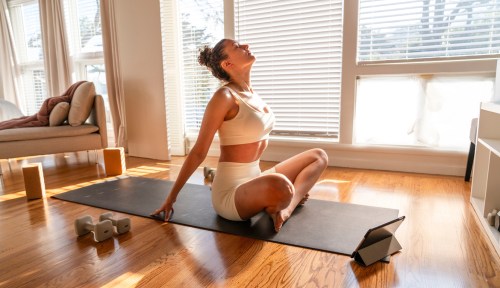 Women stretching doing gentle mobility exercises in home living room wood floor