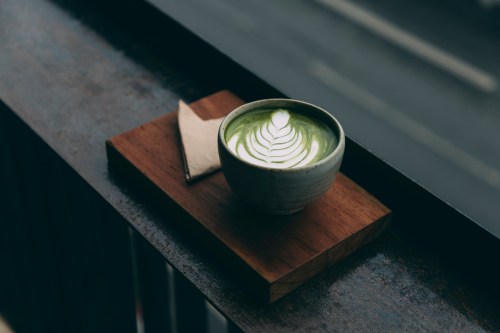 cup of matcha green tea sitting on a wooden ledge