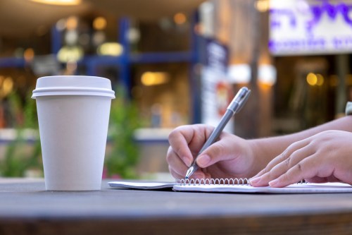 Girl taking notes in a coffee shop environment.