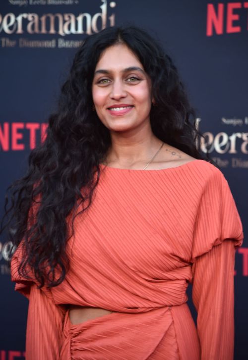 Wellness Influencer Radhi Devlukia-Shetty posing on a red carpet in an orange dress for a netflix show in 2024