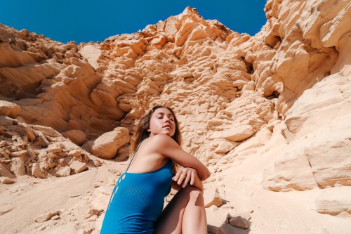 Wide angle portrait of relaxed woman sitting in the sun in a rocky desert