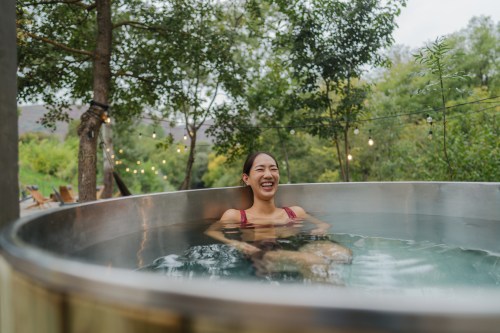 close up of person sitting in a cold tub outdoors in their bathing suit, hoping to reap cold plunge benefits