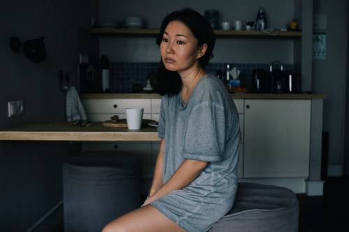 Emotionally stressed woman sitting by dining table in kitchen at home