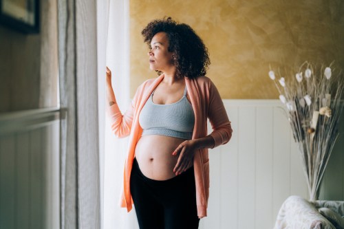 pregnant woman at home looking through the window