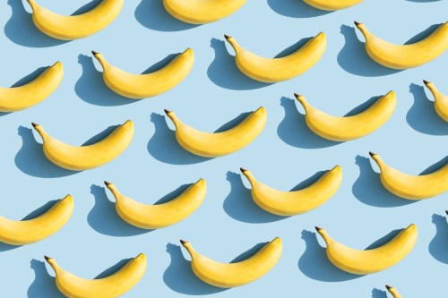 graphic photo of ripe bananas set up in rows against a light blue background