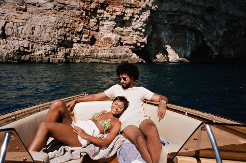 Smiling young woman resting with boyfriend in motorboat on sunny day