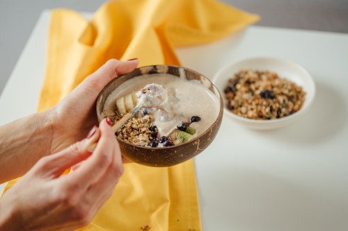 A shot of a woman holding plate coconut plate with a tasty smoothie bowl.