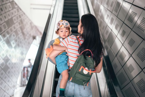 Mother And son carrying rucksack while riding an escalator, commuting to school
