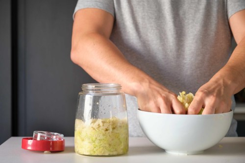 Man preparing homemade sauerkraut or fermented cabbage.