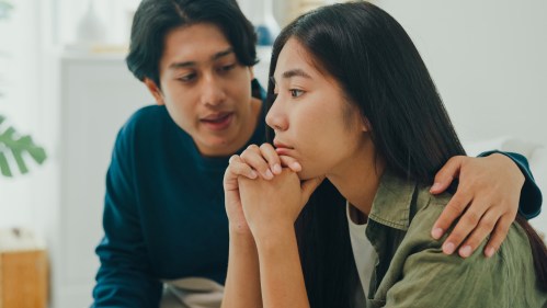 Asian sad woman crying while talking and discussing mental health problems with her husband at home. The couple communicates with each other about relationship problems with empathy concept.