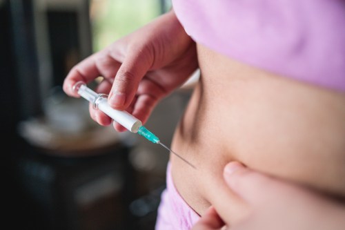 Close up of person wearing pink workout set injecting themselves with a peptide stack for muscle growth and fitness