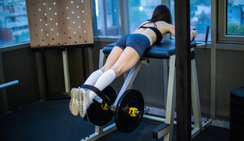 Woman doing weighted reverse hip raises in the gym